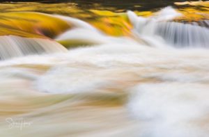 Heavily flooded Tygart Valley river flows in smooth slow motion image over waterfall in Valley Falls State Park West Virginia