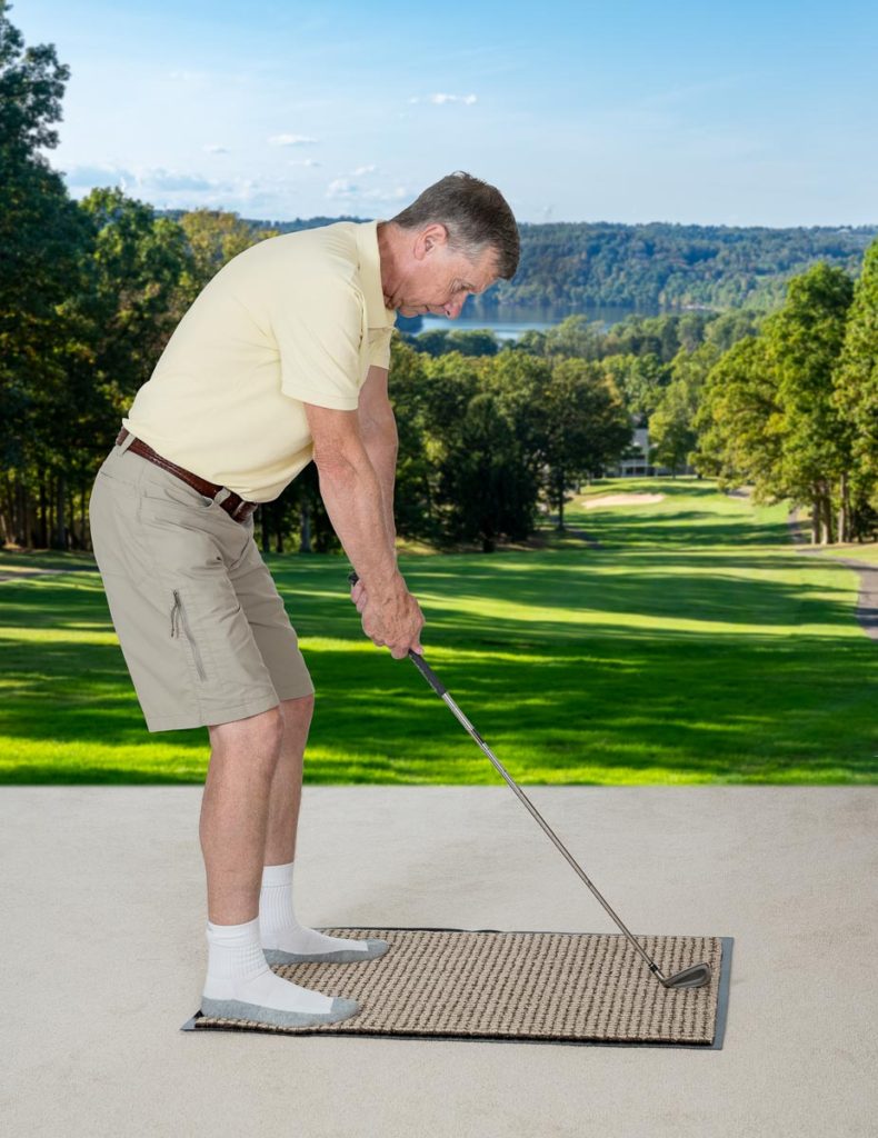 Stock photo of a man practicing golf strokes on the bedroom carpet while imagining he is outside on a course.