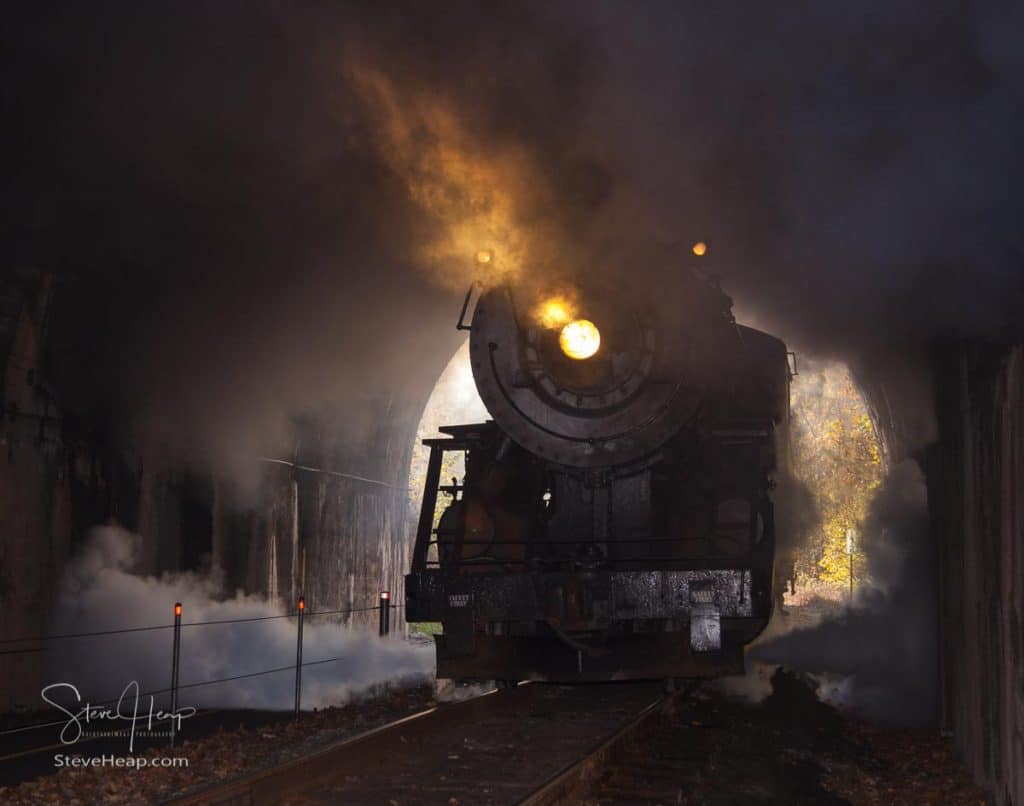 Stock photo and wall art print of an old steam train pulling into a tunnel with its headlight on
