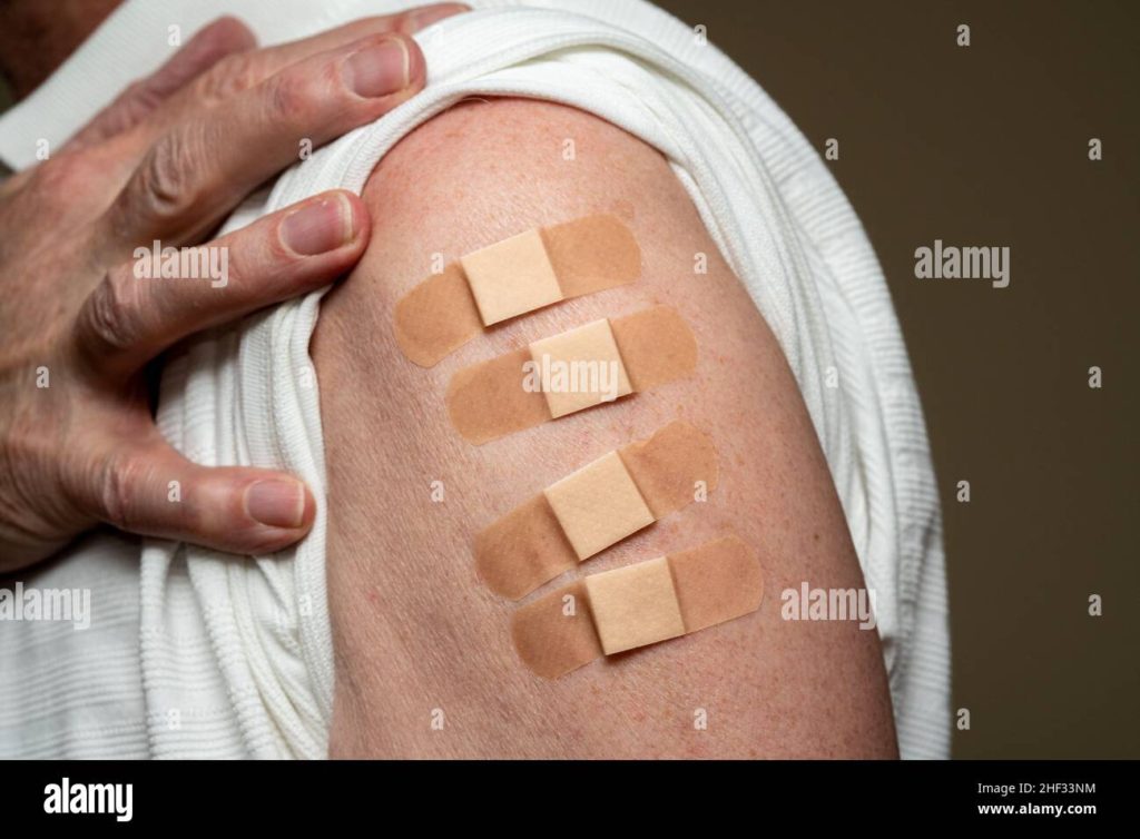 Fourth Covid-19 vaccination stock photo with arm with four sticking plasters or bandaids